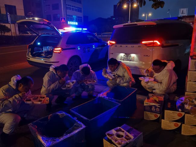 吃饭不忘守“防线”！永康市公安局交警大队坚守在疫情防控一线不离岗，常常忙得不能及时吃饭，或在寒风中捧着手中的盒饭，或蹲或站，或席地而坐，狼吞虎咽，短短几分钟就地解决了三餐。.jpg