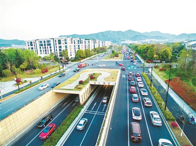 在艮山快速路延伸段建设现场,车辆穿梭,塔吊转动,工人们佩戴口罩和